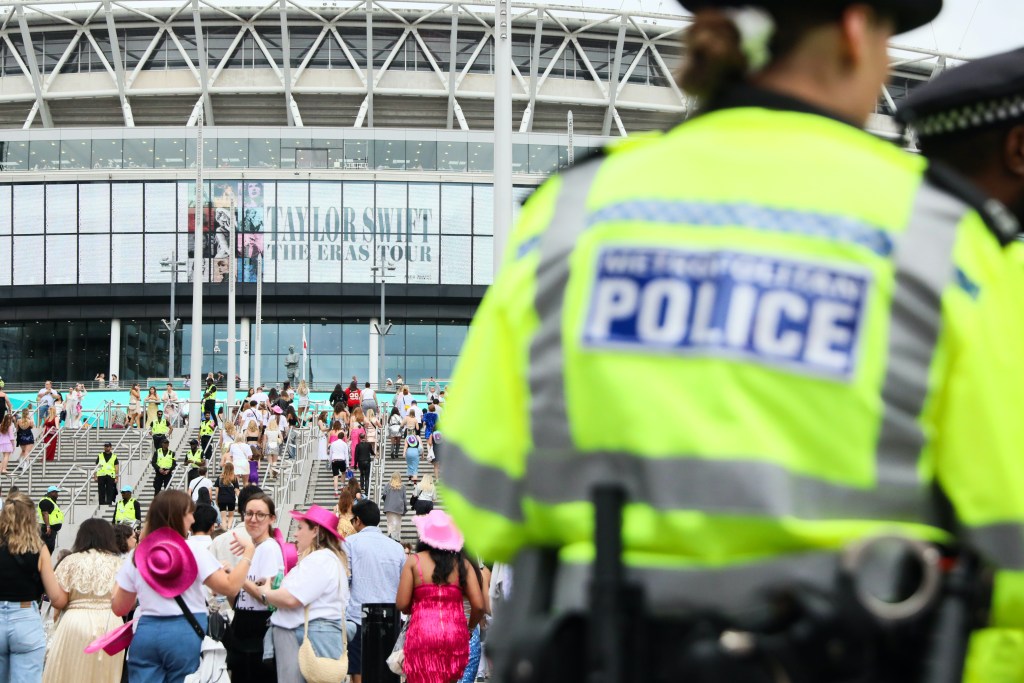 Police officers in high-visibility vests and fans entering Wembley Stadium for Taylor Swift's Eras Tour.