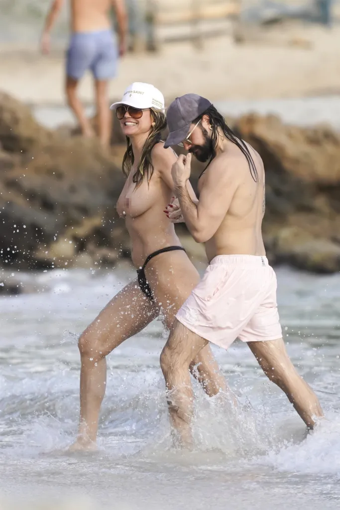 Heidi Klum and Tom Kaulitz splashing in the ocean.