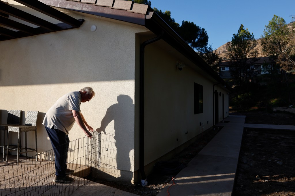Ted Koerner adjusting a fence at his newly rebuilt Altadena home.