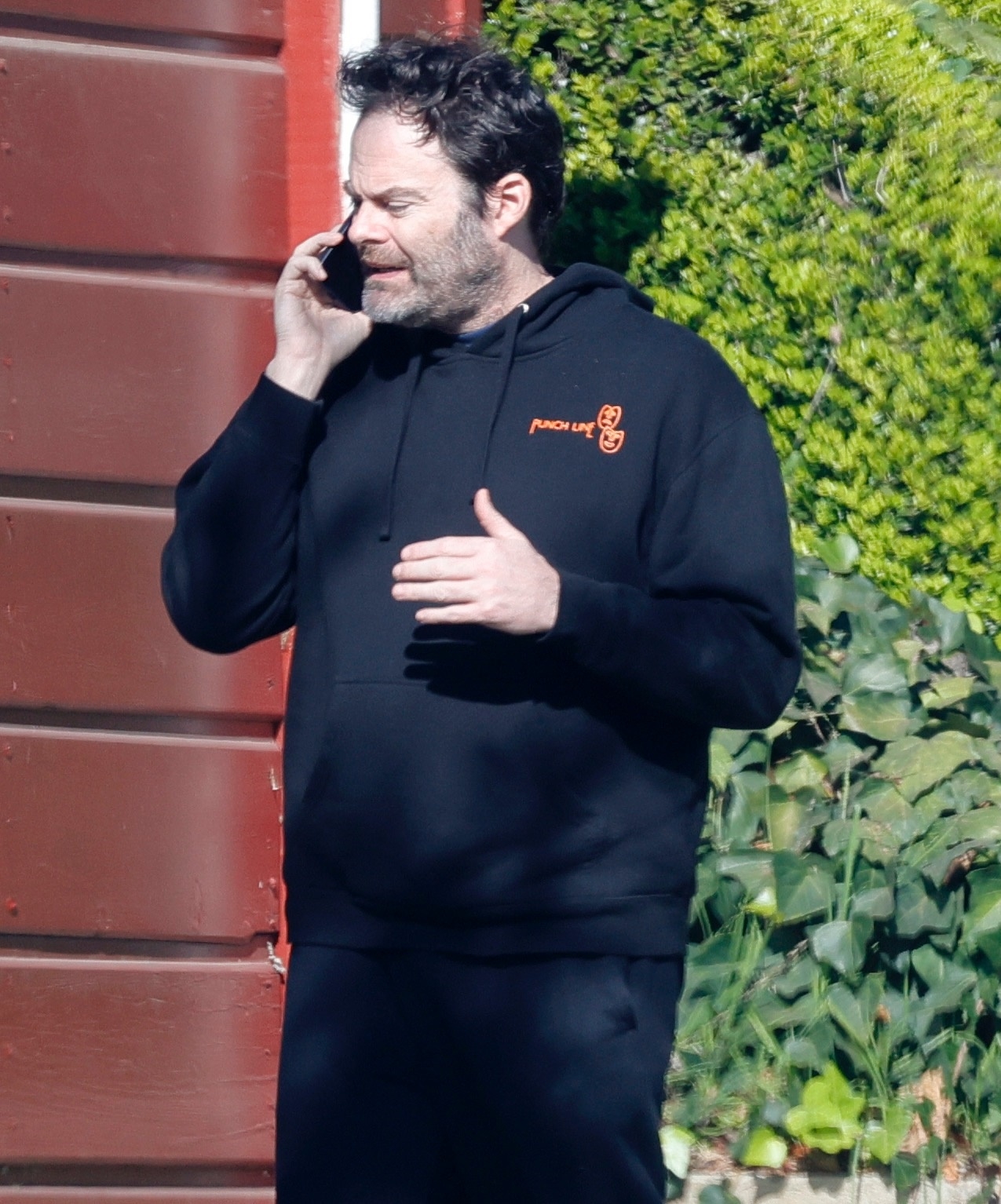 Bill Hader on an intense phone call, wearing a black hoodie with an orange 