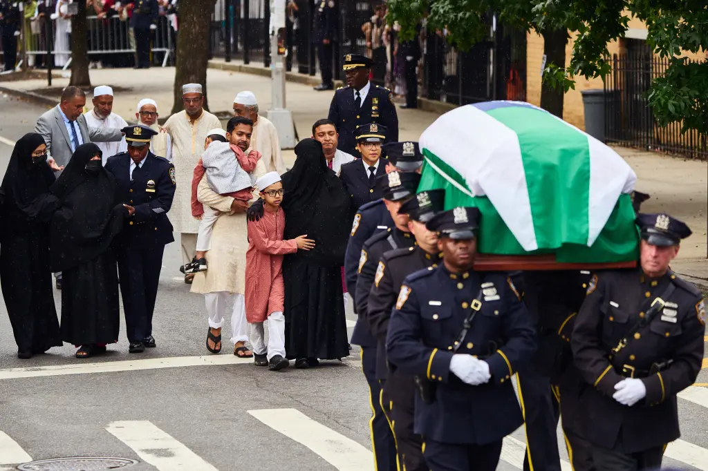 Pallbearers carry the casket of NYPD officer Didarul Islam as his family members follow during his funeral.