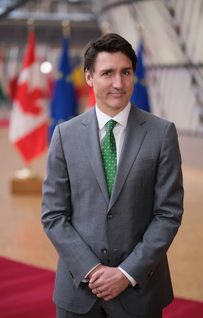 Canadian Prime Minister Justin Trudeau stands in front of Canadian and EU flags.