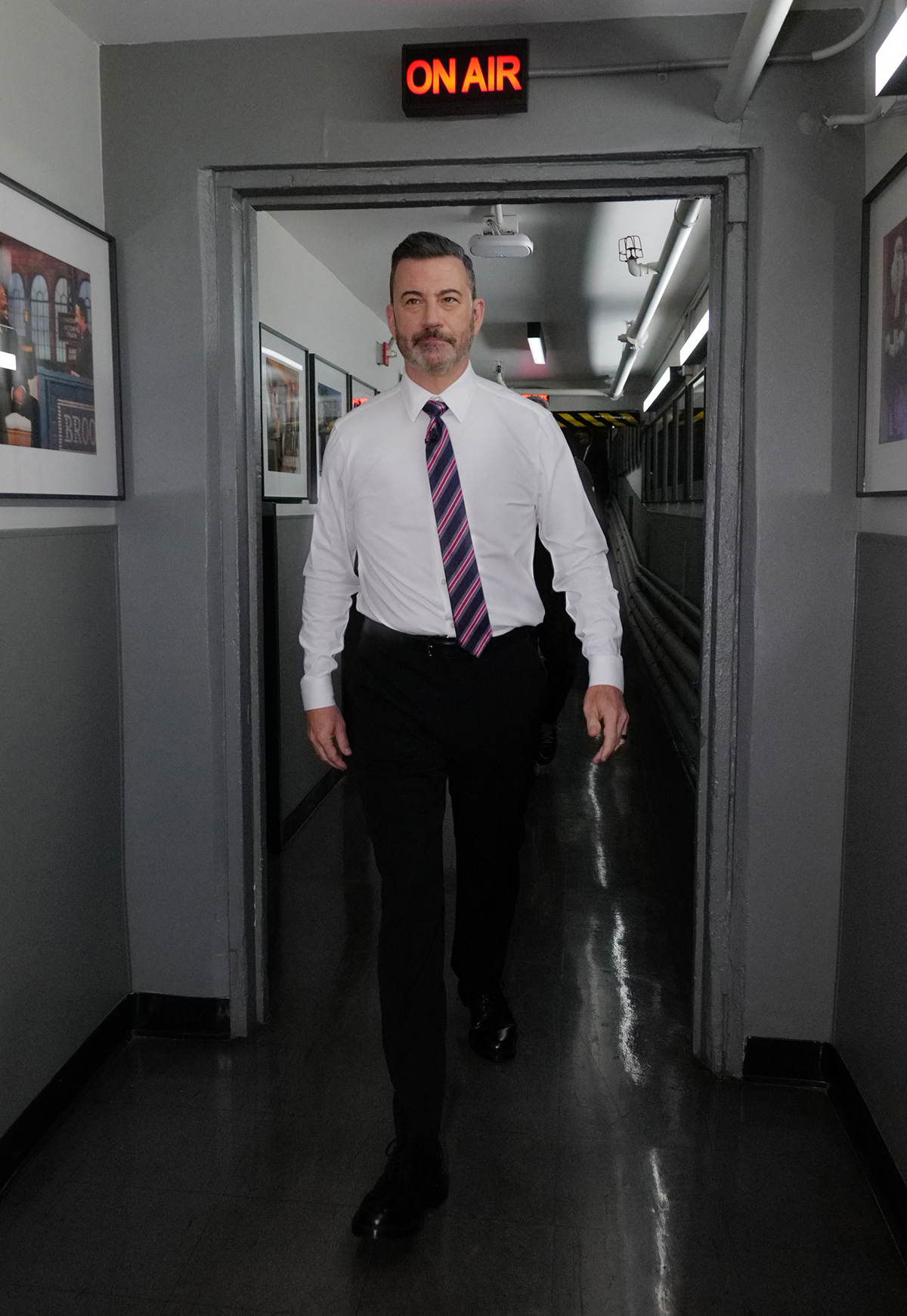 Jimmy Kimmel walking toward the camera from a hallway, with an 
