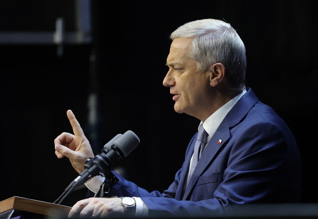 Chile's presidential candidate Jose Antonio Kast speaks at a podium with two microphones, gesturing with his right hand.