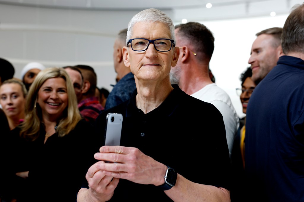 Apple CEO Tim Cook holding a new iPhone.