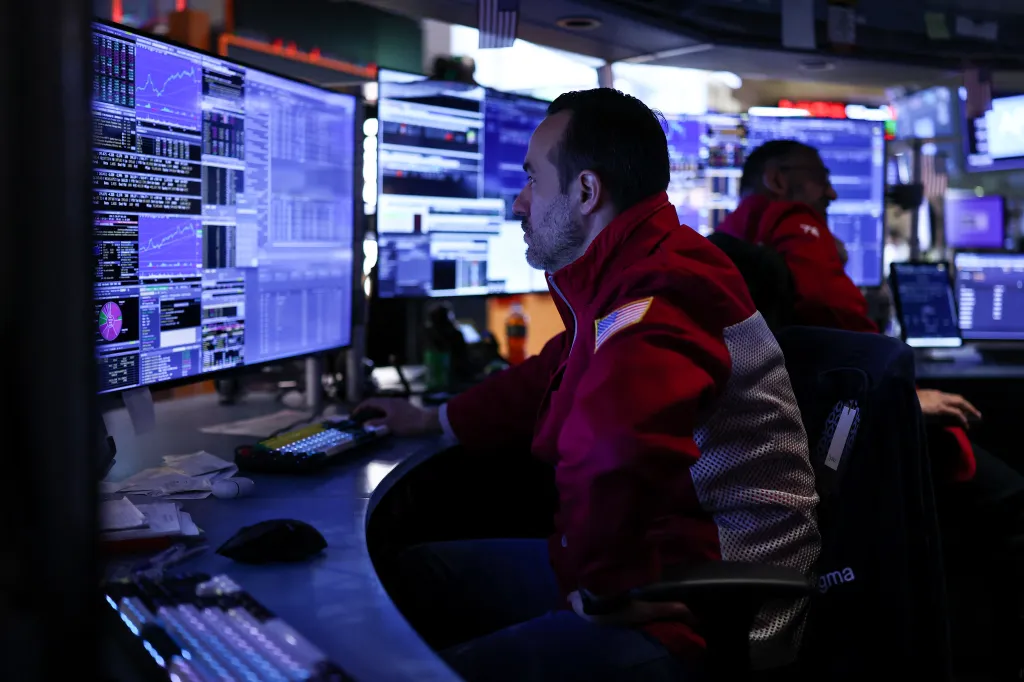 A stock trader views multiple screens of financial data on the floor of the New York Stock Exchange.