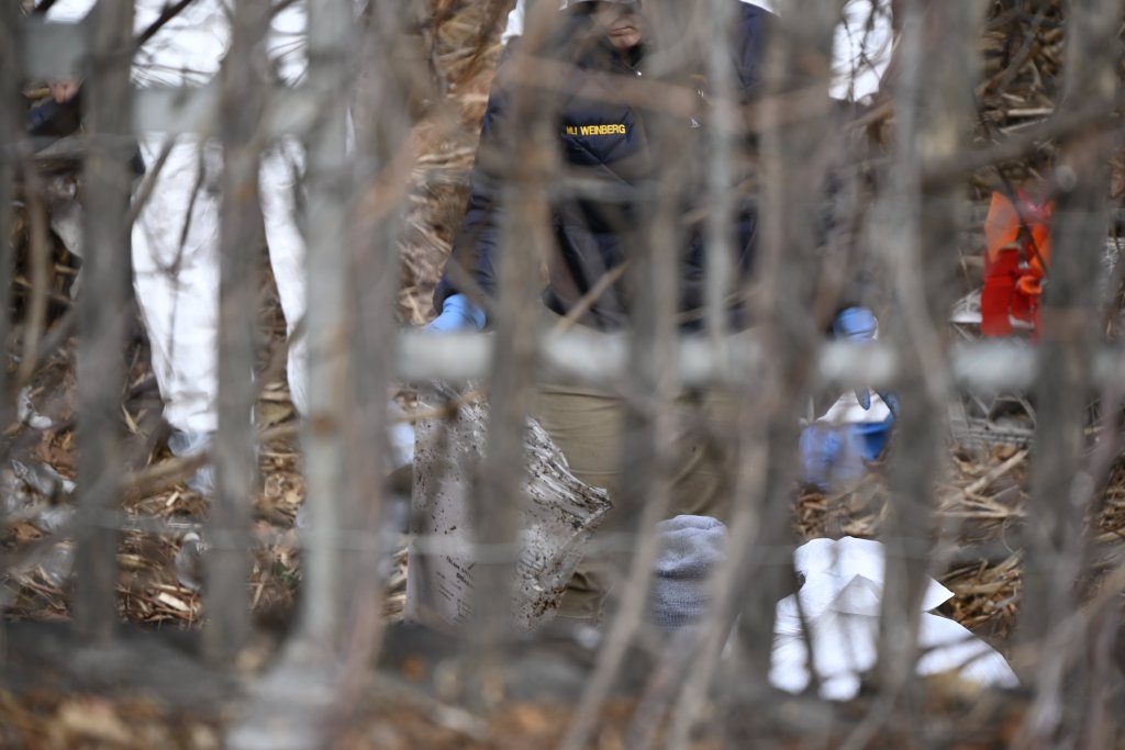 Forensic investigators in protective gear examining human remains at a crime scene.