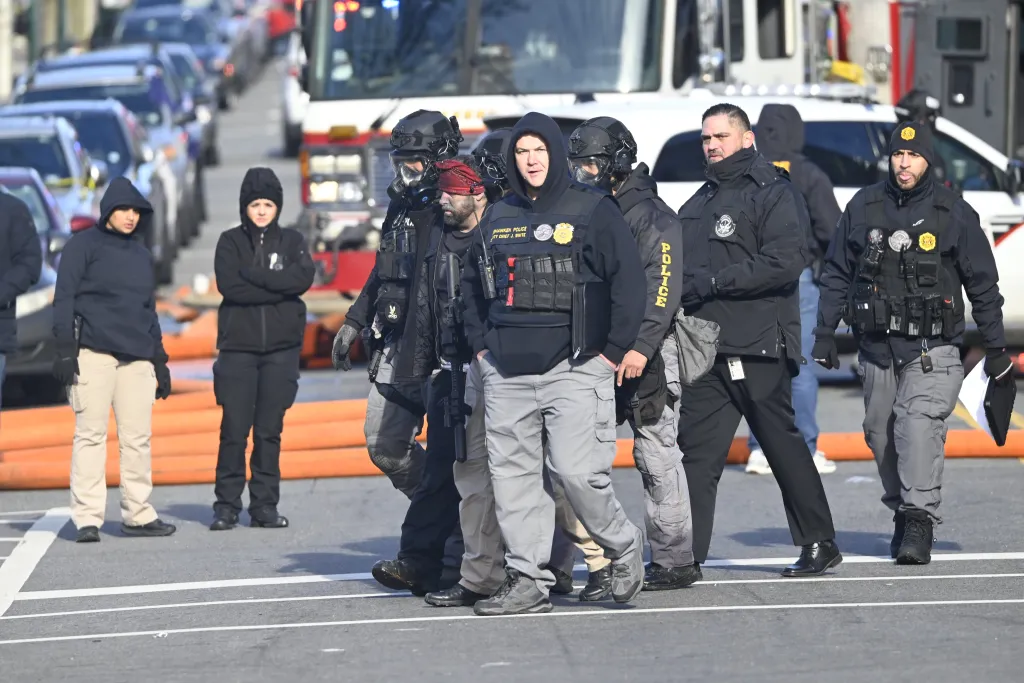 SWAT team members and other law enforcement personnel at the scene of a fatal bow-and-arrow killing and standoff.