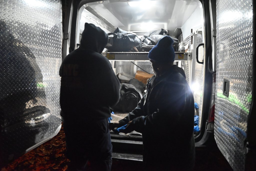 OCME personnel removing human remains from the back of a truck.