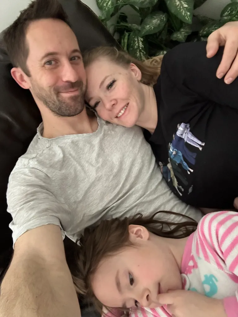 Kendal Seymour, Elleshia Seymour, and one of their children laying on a couch together.