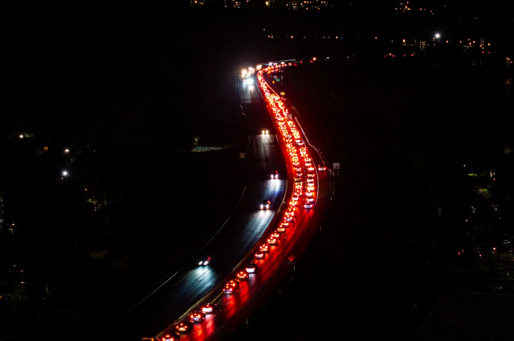 Aerial view of congested traffic exiting a city on a dark highway at night.