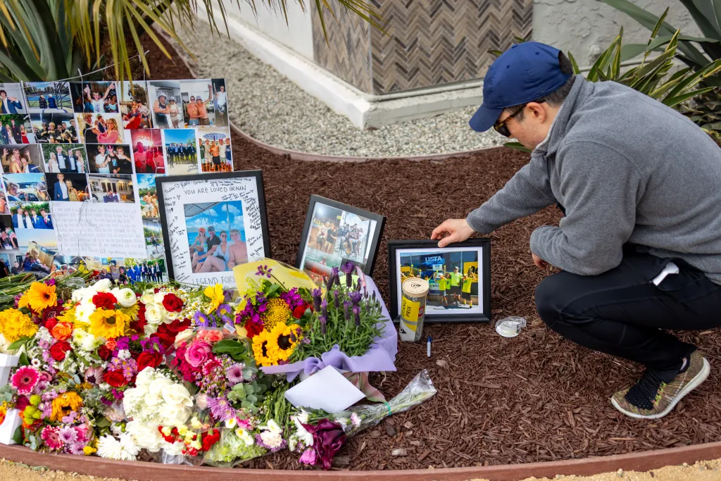 A man placing a photo at a memorial for Braun Levi.
