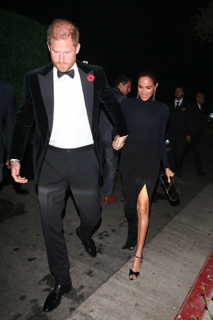 Prince Harry in a black tuxedo and Meghan Markle in a black dress with a thigh-high slit, holding hands.