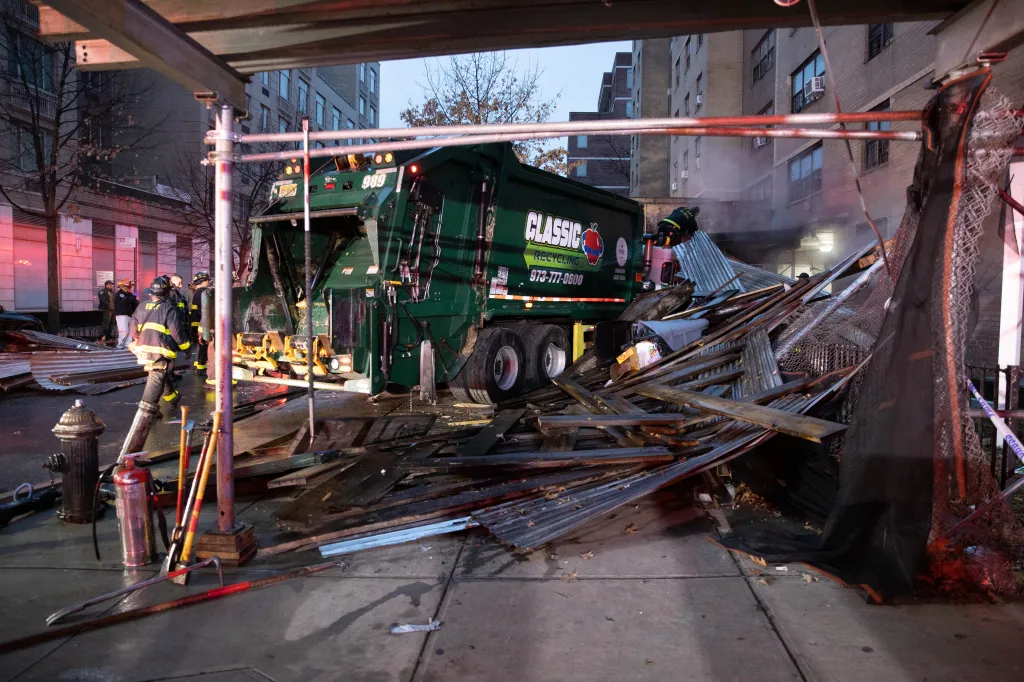 A private garbage truck crashed into a scaffold and cars, with firefighters at the scene.