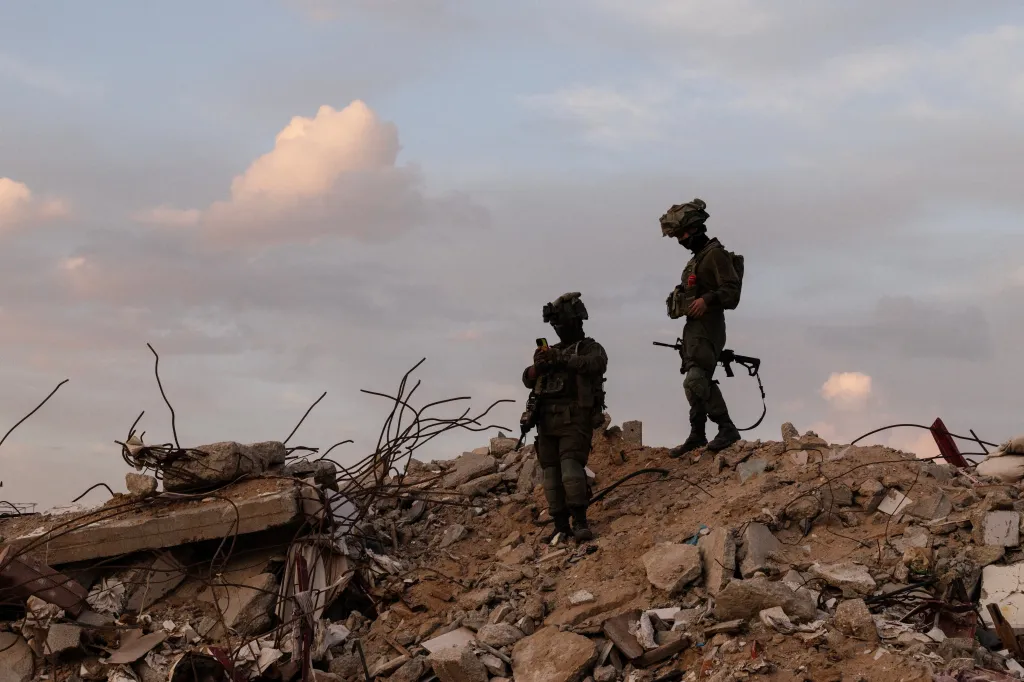 Two Israeli soldiers stand on a pile of rubble in Rafah.