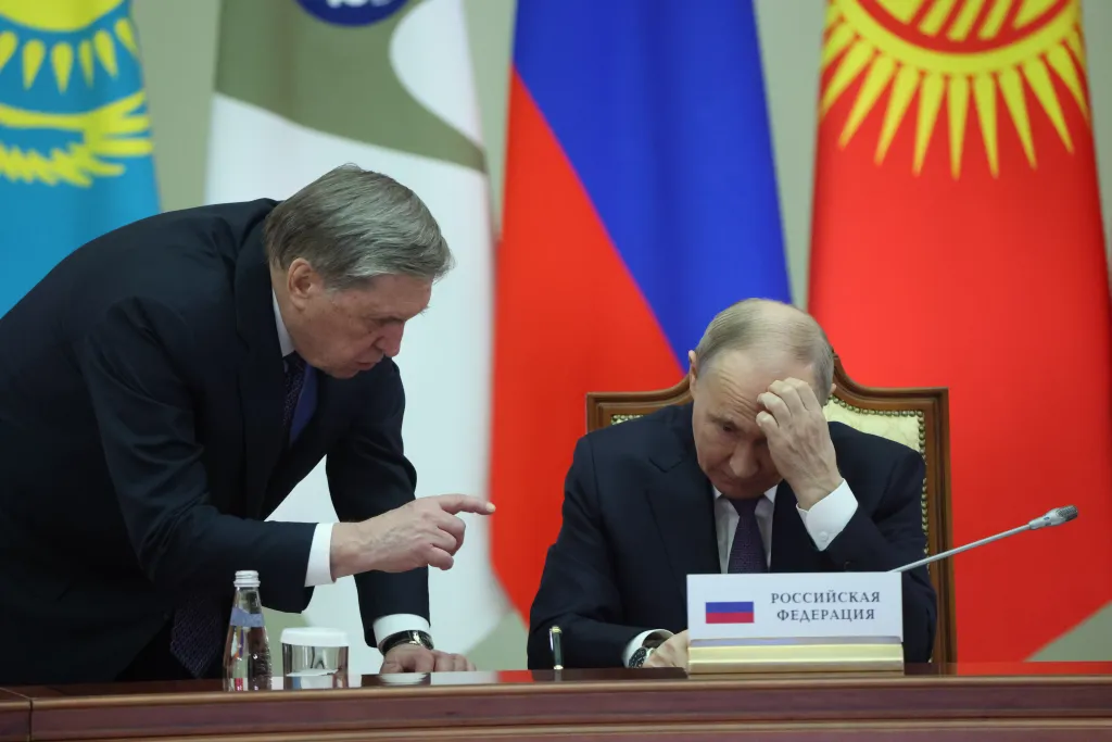 Russian President Vladimir Putin (R) listens to his aide Yuri Ushakov (L) during the Eurasian Economic Union Summit, on December 21, 2025 in Saint Petersburg, Russia.