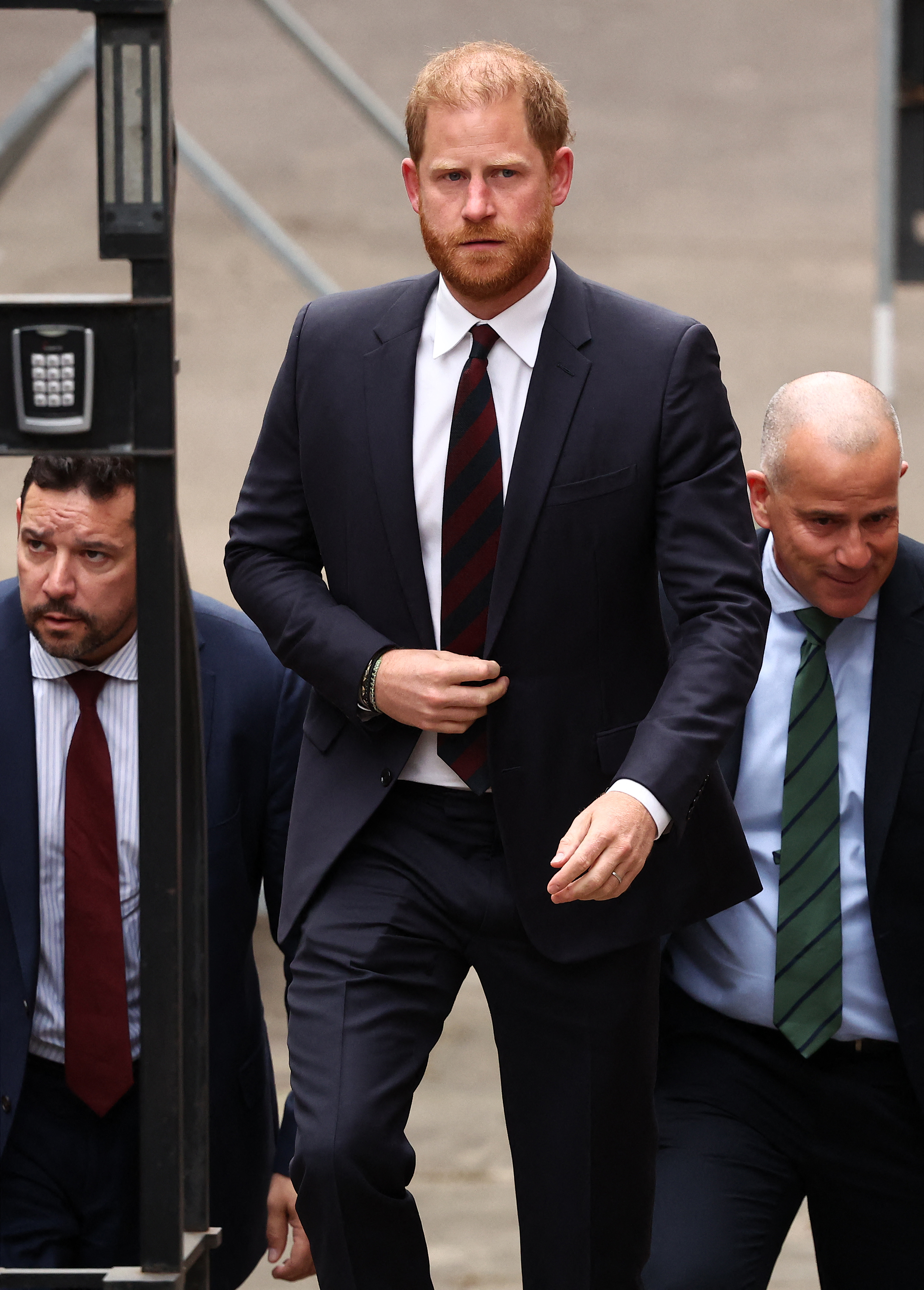 Prince Harry walking with security detail at the Royal Courts of Justice.