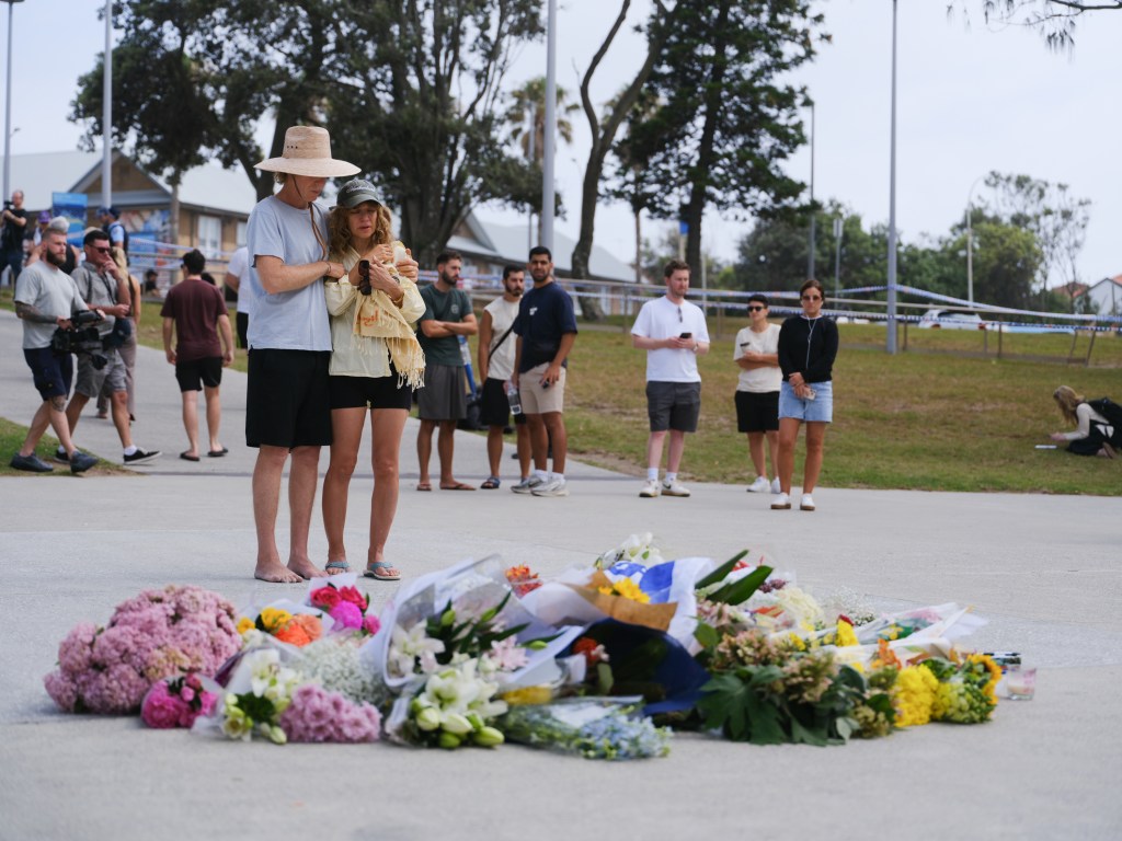 People gather around flowers laid at Bondi Beach in Sydney, Australia, following a mass shooting.