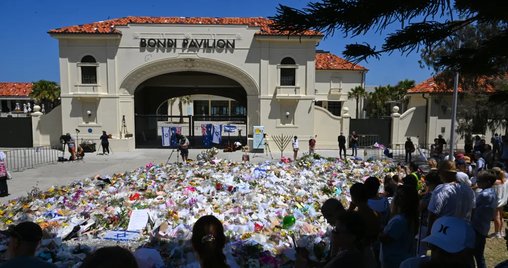 People gather at a flower memorial beside Bondi Pavilion.