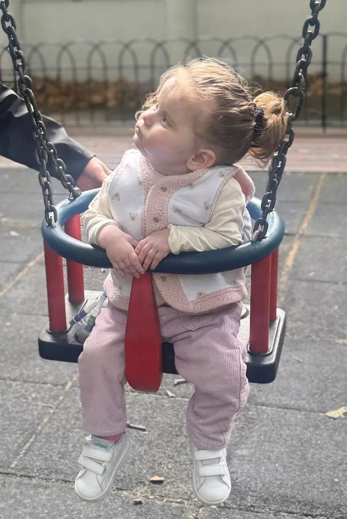 Ruby, a young girl, sitting in a swing.