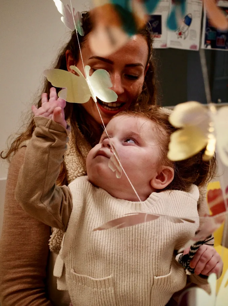 Elle Daniel holding her daughter Ruby, who is reaching for decorative butterflies.