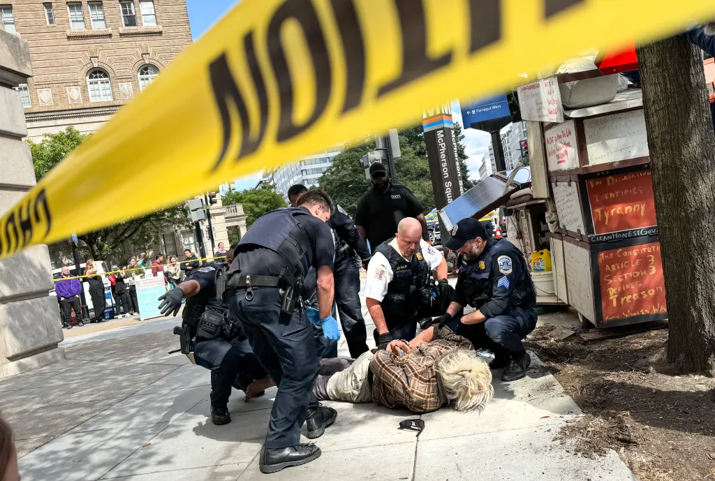 Police officers detain a person from an encampment near the McPherson Square metro station in Washington, DC.