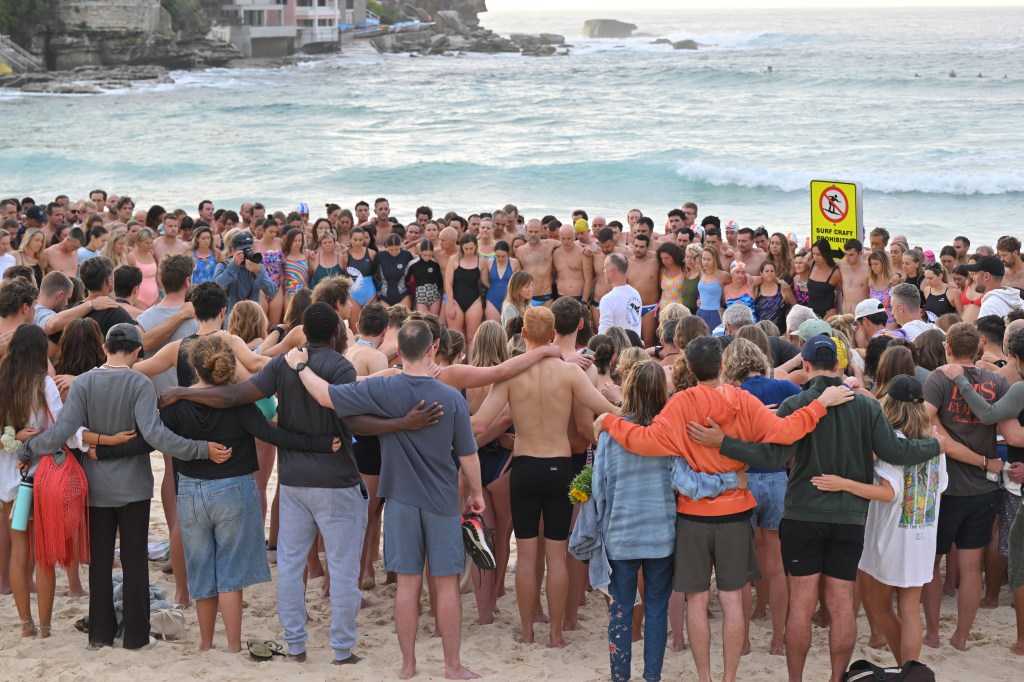 People on Bondi Beach at a morning vigil for victims of the Bondi Beach shooting.