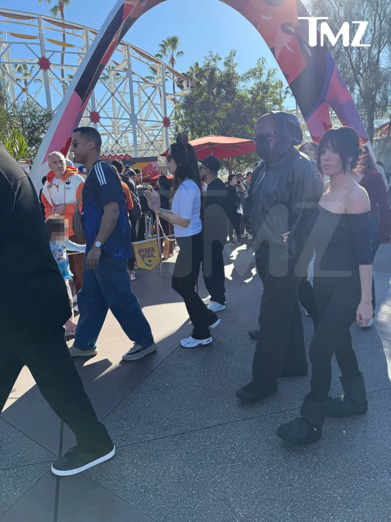 Bianca Censori and Kanye West walking through Disneyland.