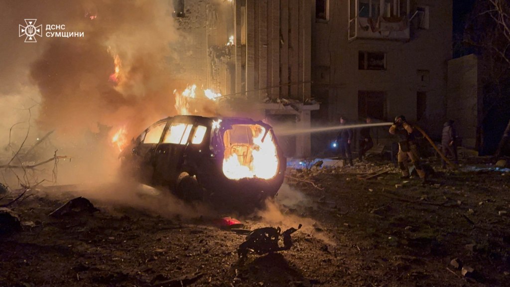 firefighters working to extinguish a fire following a drone attack to a residential building in Okhtyrka, Sumy region
