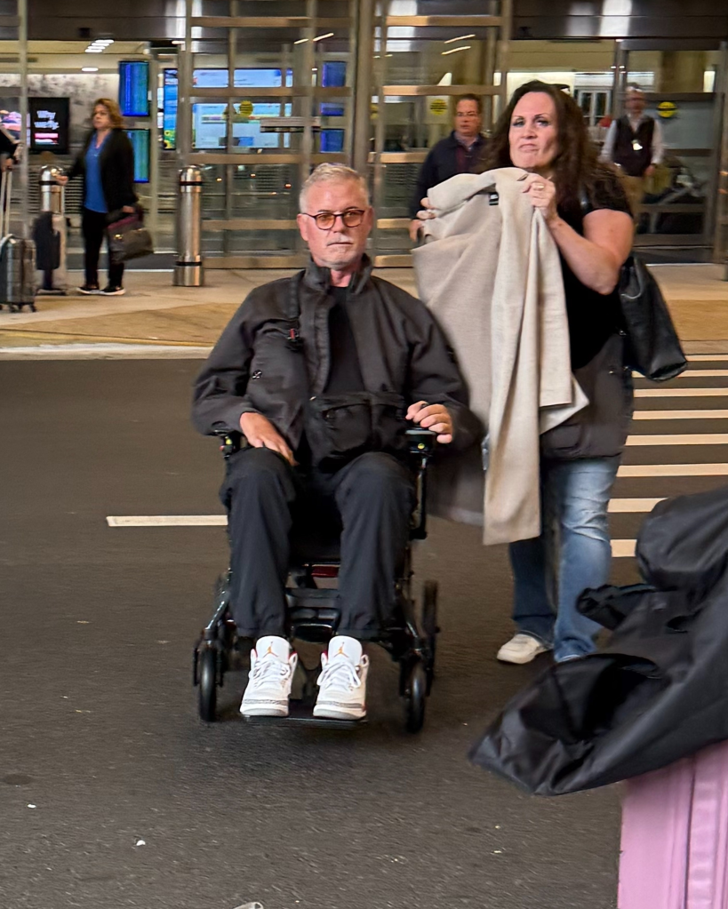 Eric Dane in a wheelchair with a woman holding a blanket.