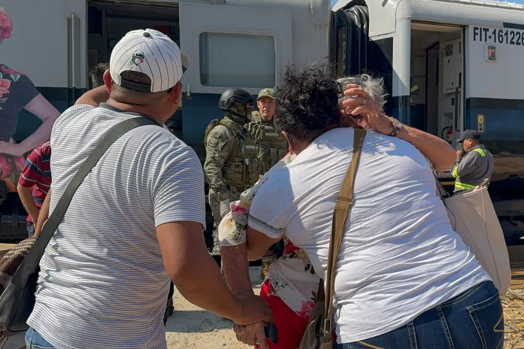 Two train passengers hug after being rescued by Mexican Army soldiers and Civil Protection members.