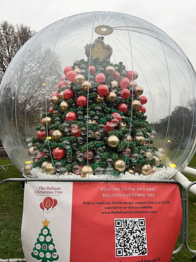 A 25-foot-tall Christmas tree made of 100,000 balloons, enclosed in a clear inflatable dome, with signage for 