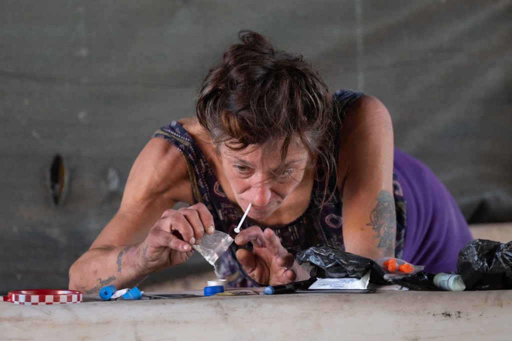 Woman preparing to snort substances with a small white spoon.