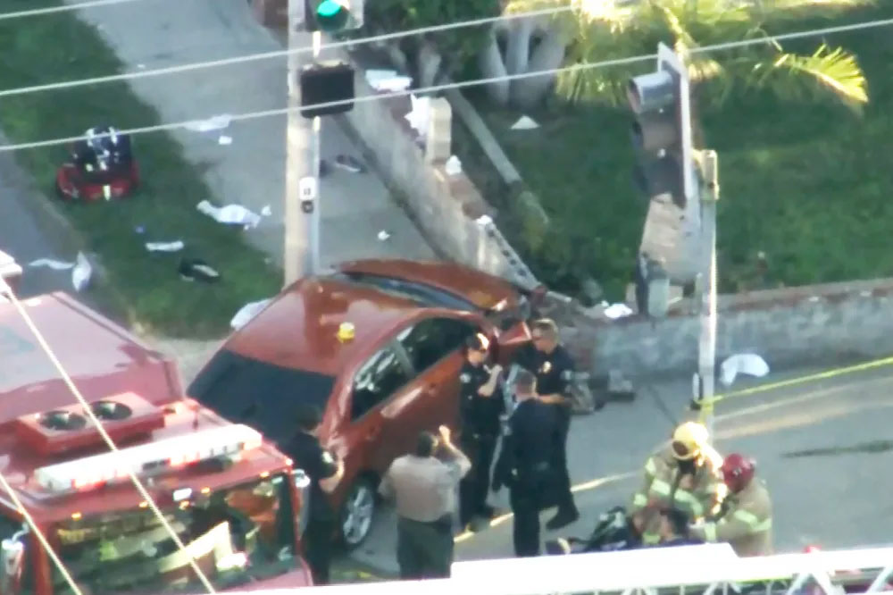 An orange car involved in an accident, with police and firefighters on scene.