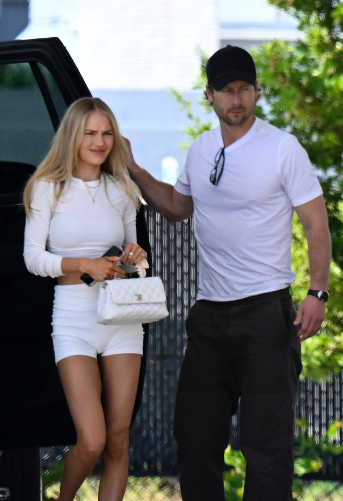 Glen Powell and Michelle Randolph walking together, with Powell holding a door open for Randolph.