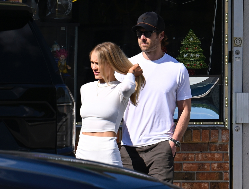 Glen Powell and Michelle Randolph walking together with Powell holding a door for Randolph.