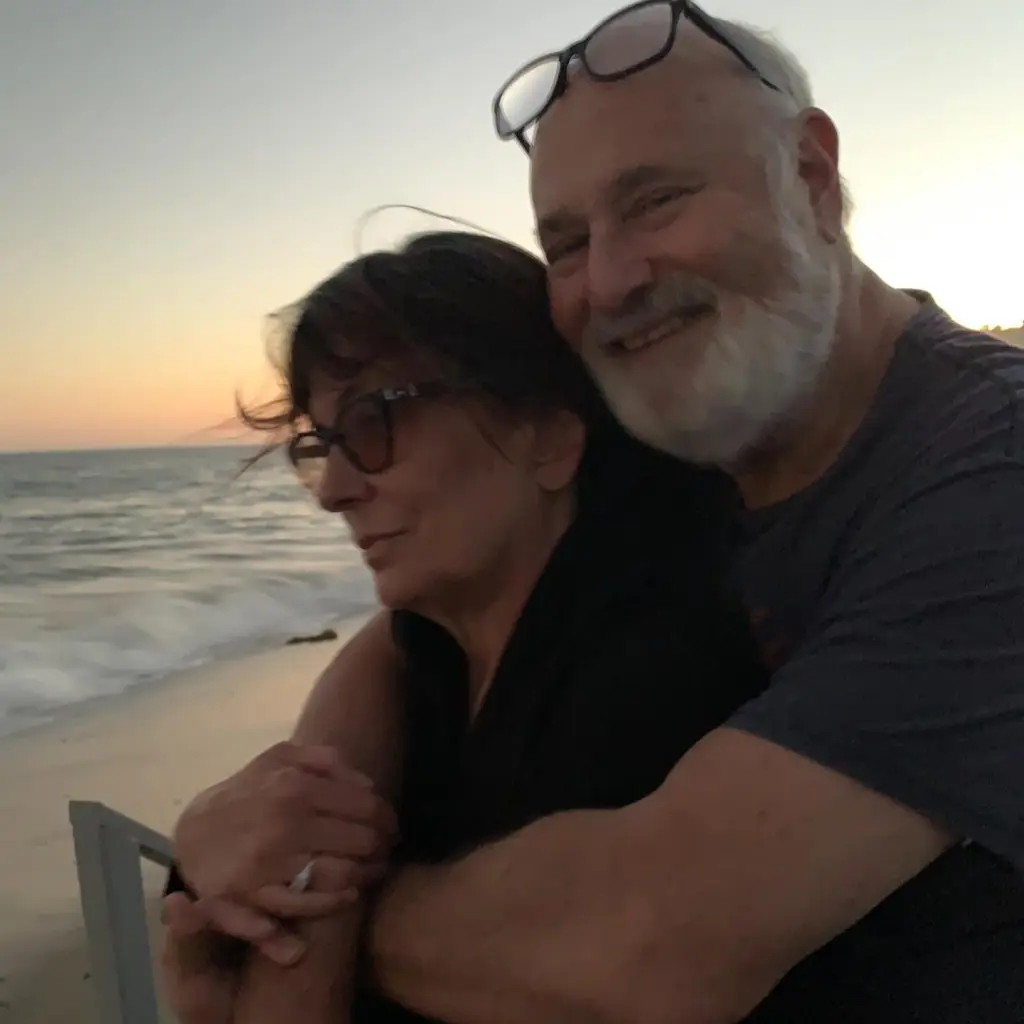 Michele and Rob Reiner embracing on a beach at sunset.