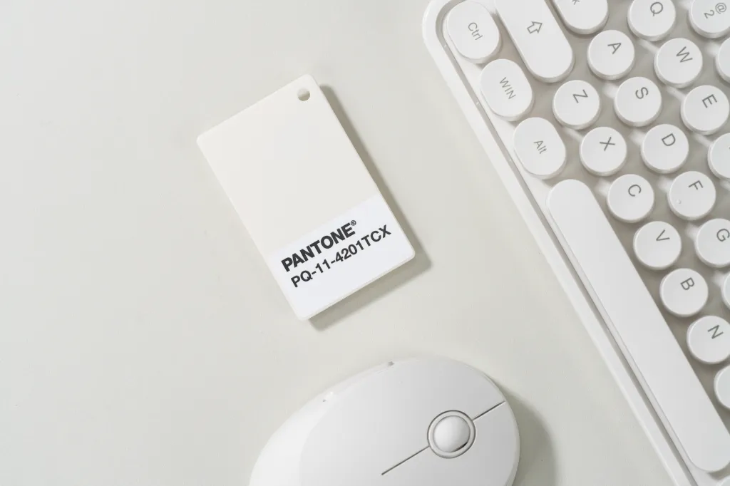 A Pantone color swatch for PANTONE PQ-11-4201TCX, Cloud Dancer, shown with a white computer mouse and keyboard.