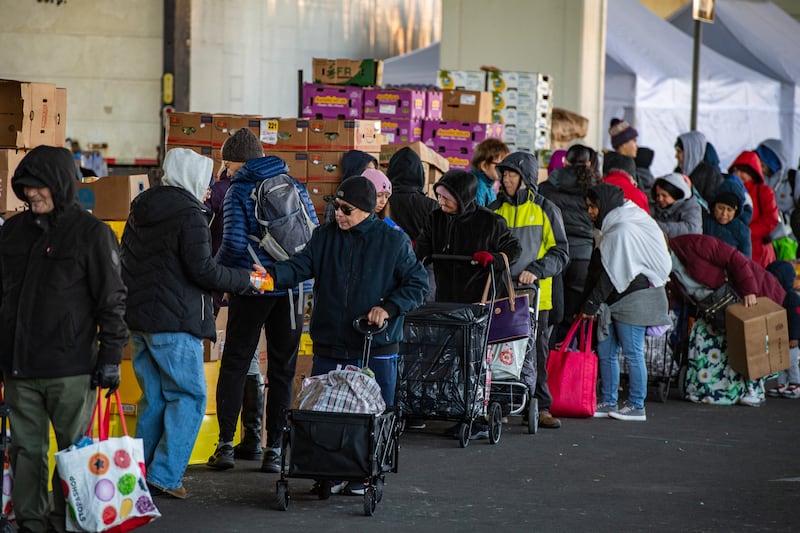 Workers and volunteers hand out food to people in line at La Colaborativa's food pantry in Chelsea, Massachusetts