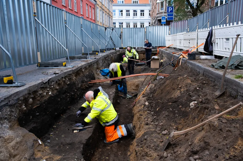 Archaeologists excavating a trench in the street.