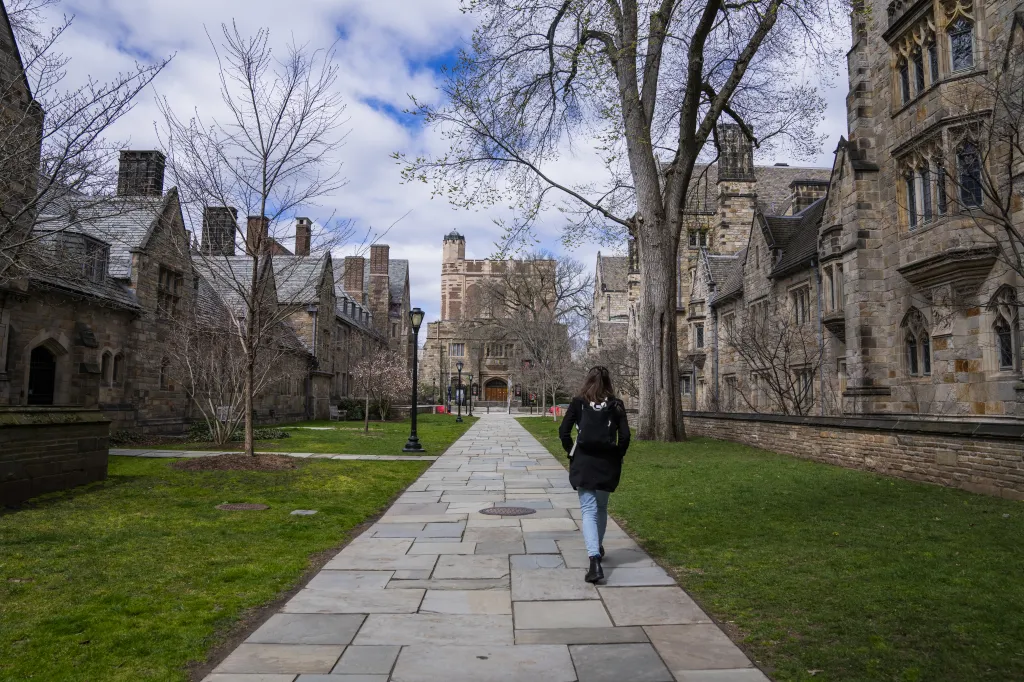 A student walks along Library Walk at Yale University campus.