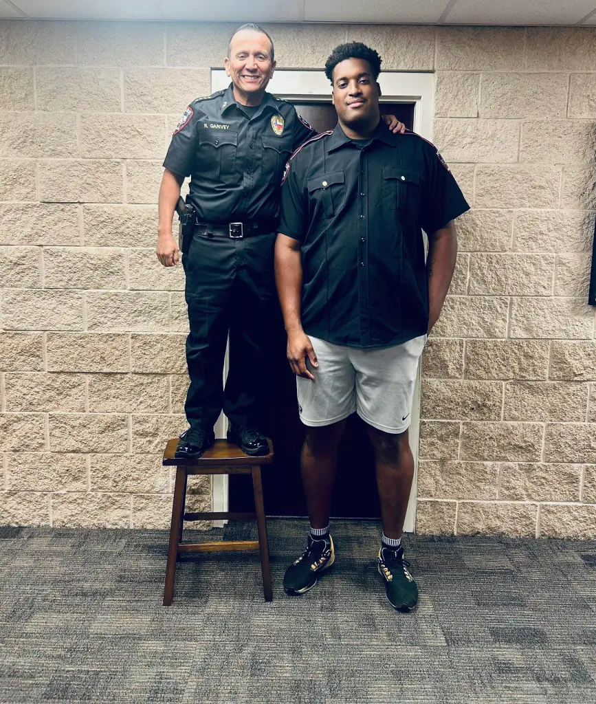 Kemah Police Chief Raymond Garivey stands on a stool to take a picture with police cadet Jordan Wilmore.