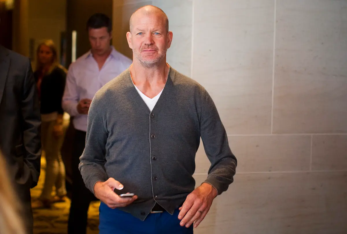 Chip Wilson walking with a cellphone in his hand.