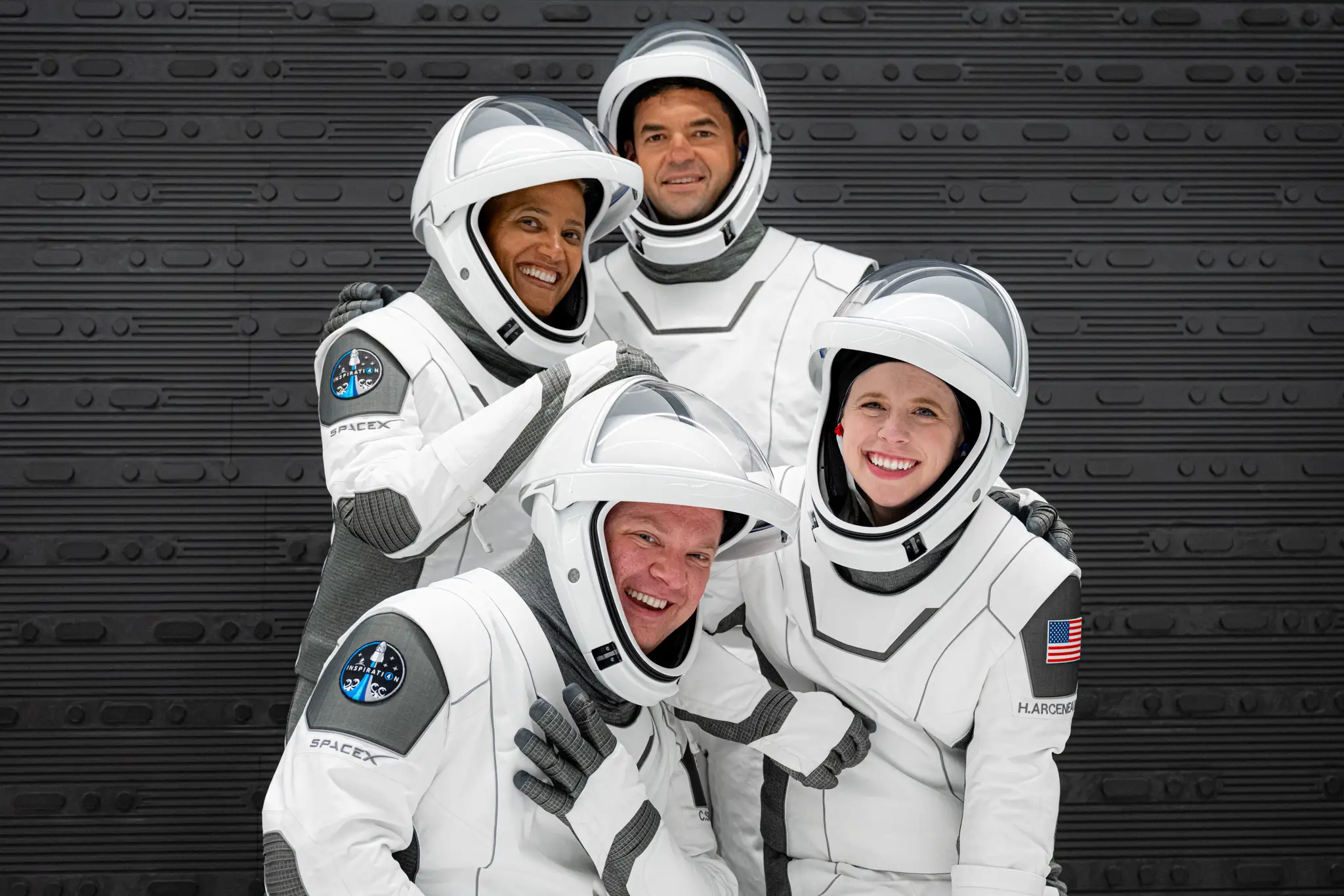 inspiration4 crew members pose in spacesuits in front of grey wall