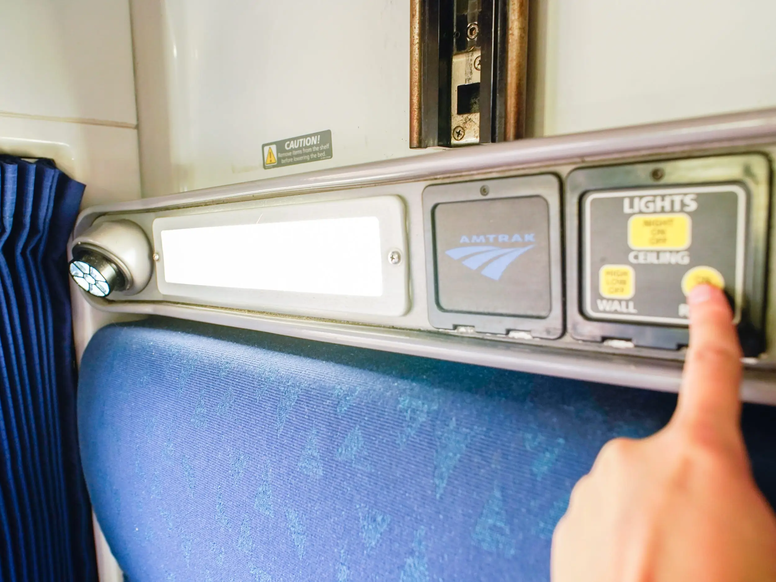 The author's finger presses a button turning on a light in her roomette