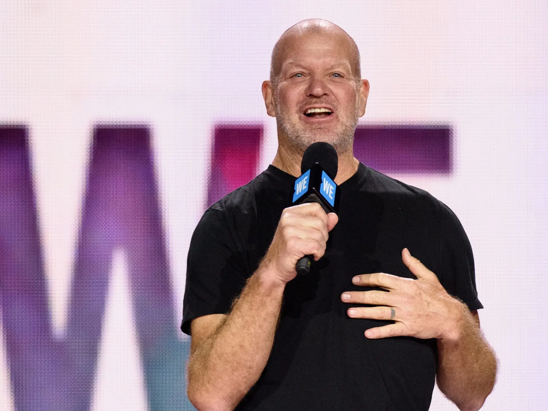 chip wilson on stage with mic, smiling, wearing black jeans and black t shirt