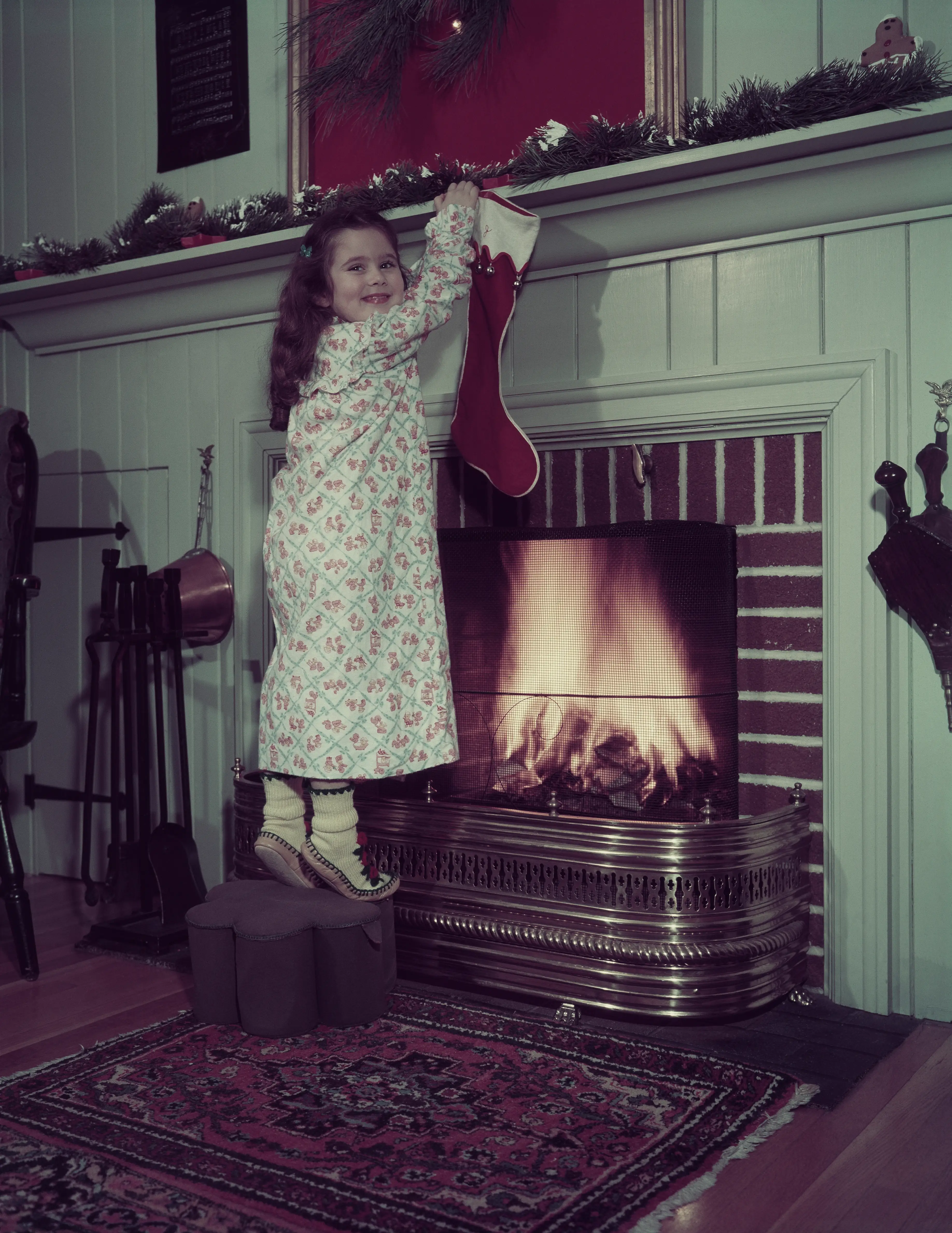 A girl hangs a stocking on a fireplace in 1951