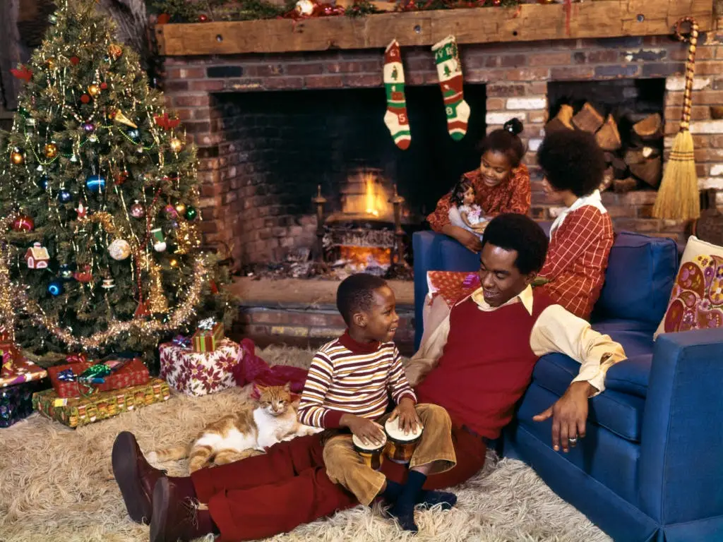 A family sits by a fireplace and a Christmas tree in 1975