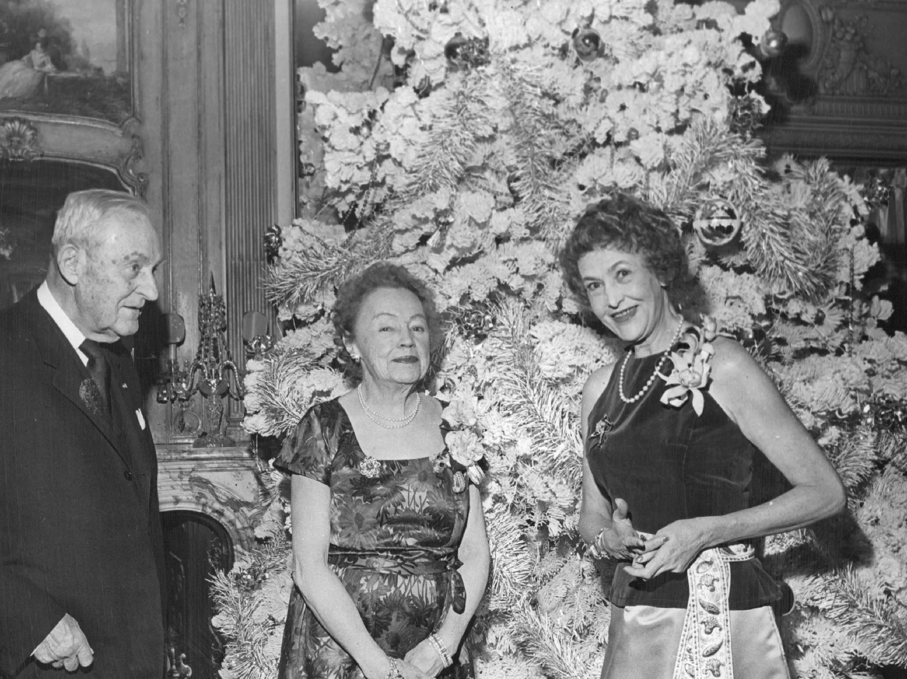 People stand in front of a flocked tree in 1963.
