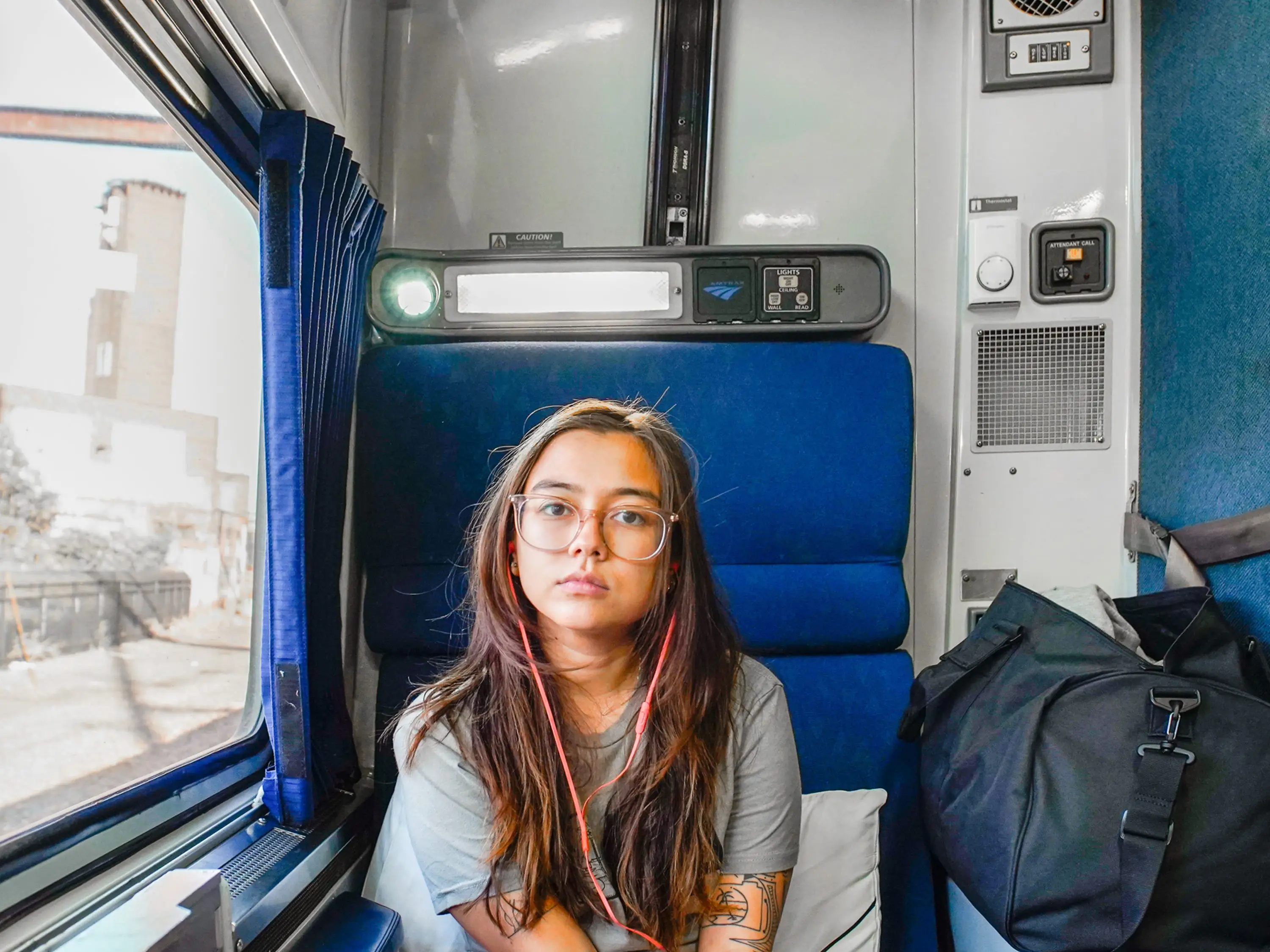 The author sits in a roomette with a window on the left side and a duffel on the right.